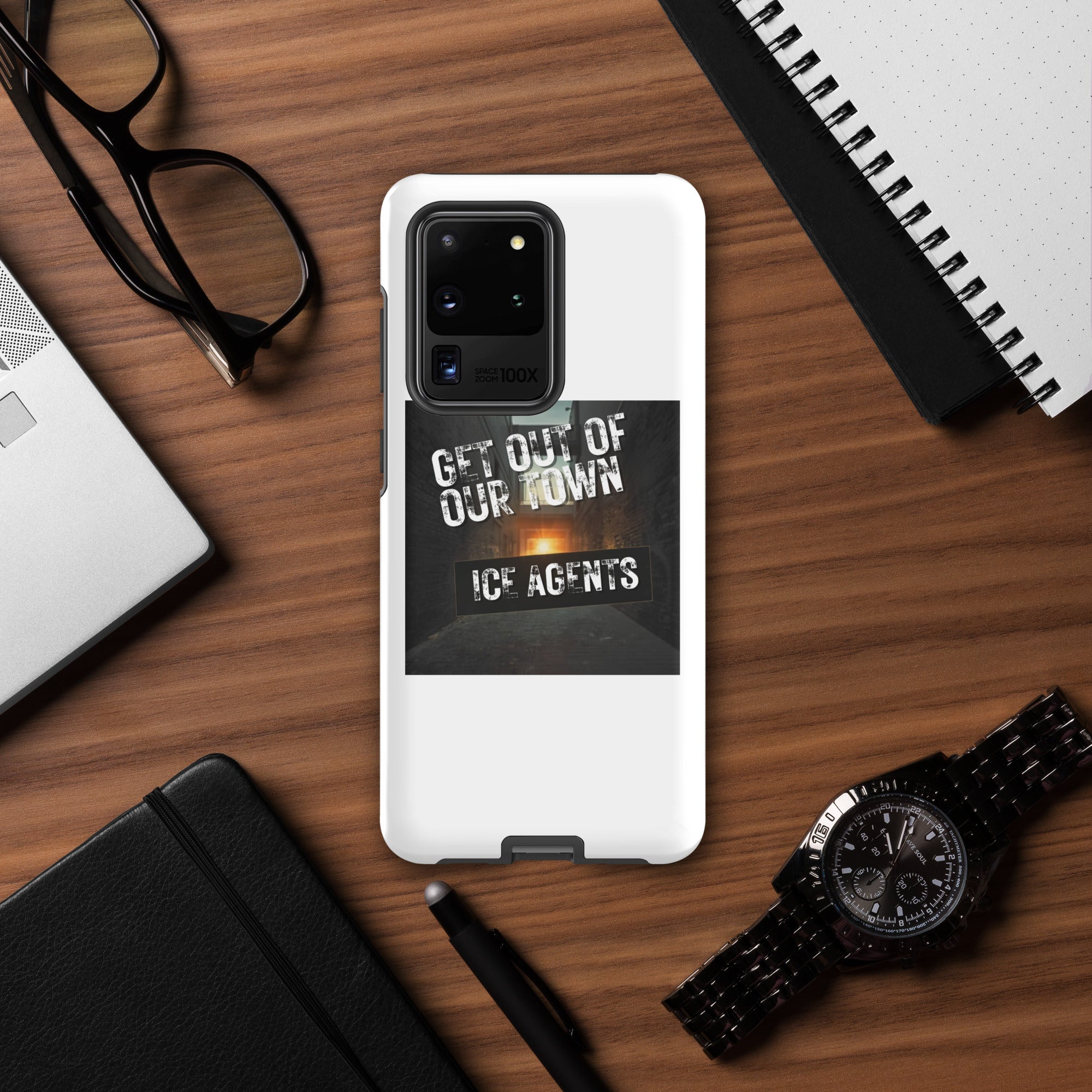 White Samsung case with “Get Out Of Our Town” “Ice Agents” graphic; visible camera lenses.