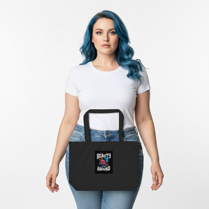 Organic cotton tote bag held by model, black with front graphic visible