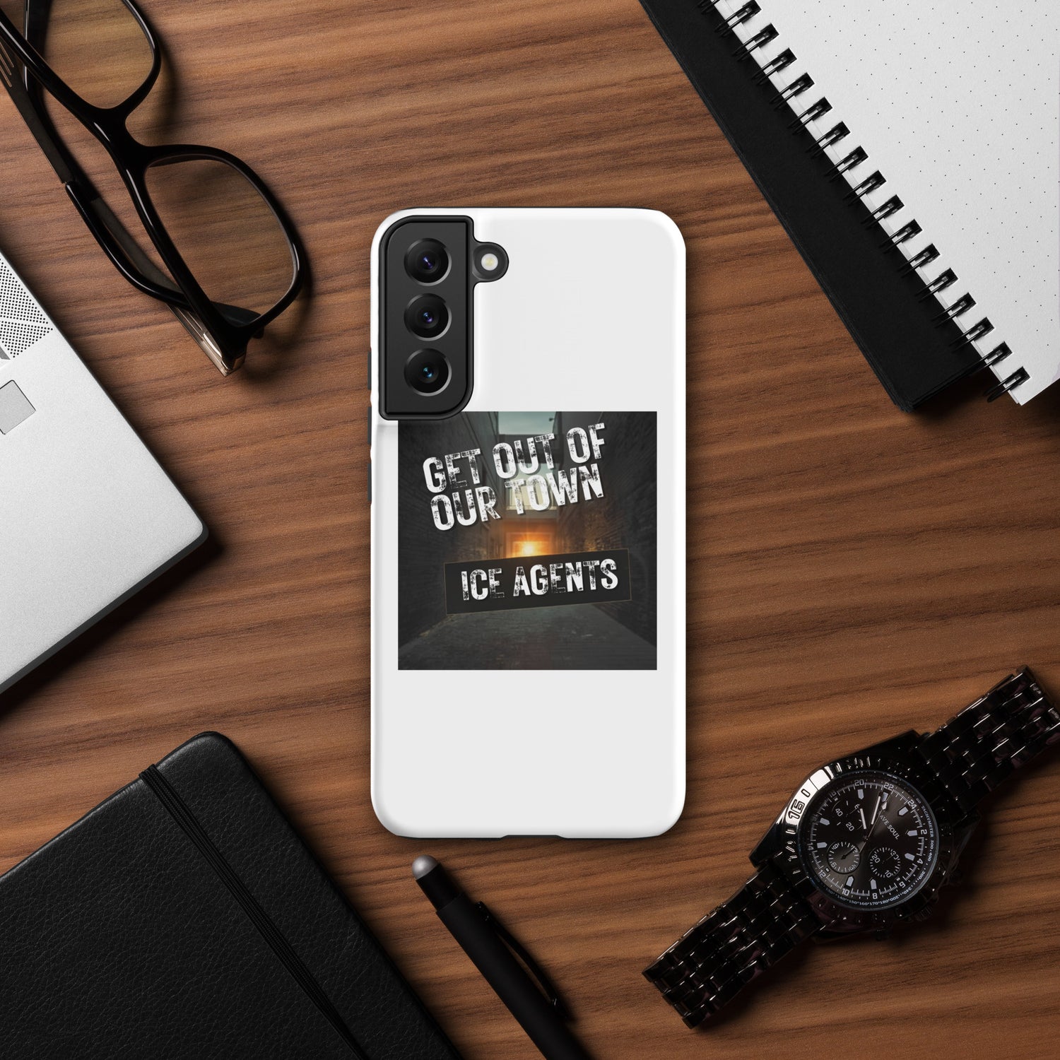 White rear phone case with black camera module and bold “GET OUT OF OUR TOWN” print