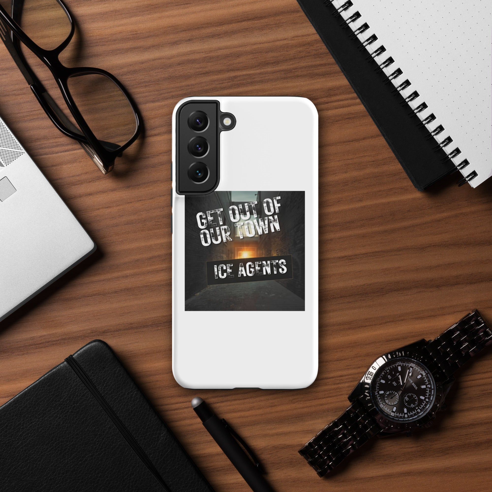White rear phone case with black camera module and bold “GET OUT OF OUR TOWN” print