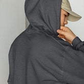 Unisex dark heather hoodie close-up, hand holding the hood opening