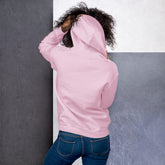 Light pink unisex hoodie worn sideways view, front pocket and hood visible