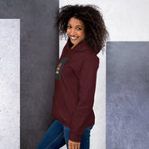 Unisex maroon pullover hoodie with hood, kangaroo pocket, and front graphic patch (side view)