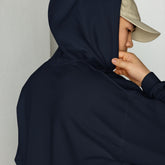 Navy unisex hoodie close-up with drawstring hood and front pouch, hand holding collar