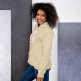 Cream unisex hoodie with hood, front pouch pocket, and chest graphic patch.